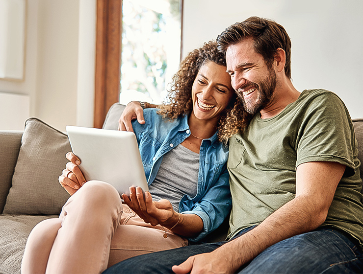 A happy couple making a reservation on a tablet