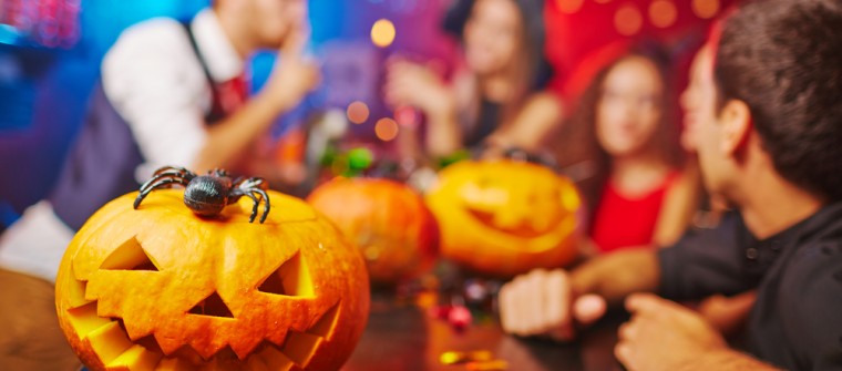 halloween pumpkins on bar with people socializing in background
