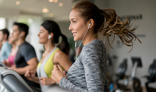 woman running on treadmill with headphones on