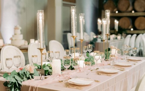 rectangular table set for a wedding with long candles and pink cloths