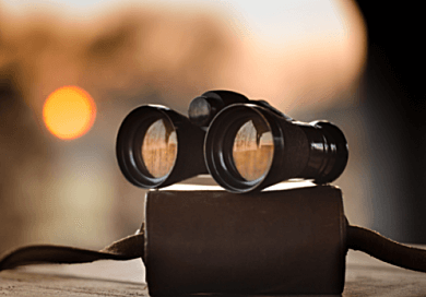 pair of binoculars sitting on table in front of sunset