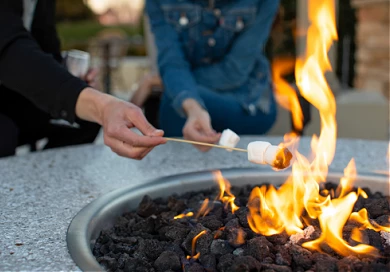 man and woman toasting marshmellows over fire