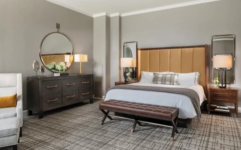 bed in suite with dresser and round mirror hanging over it