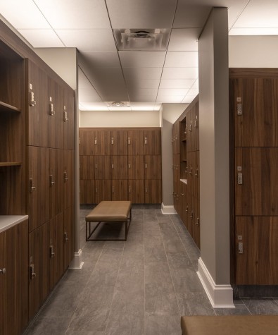 spa locker room with lockers in rows of three, benches, and a shelf with towels