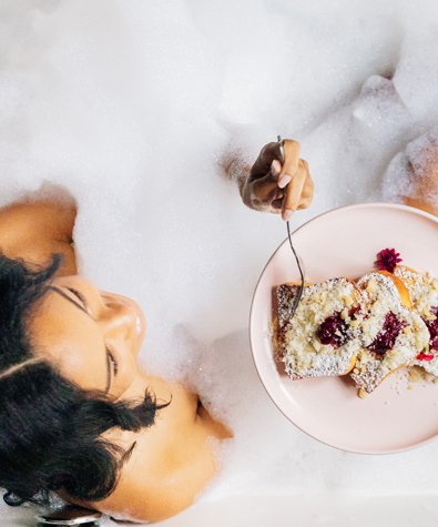 woman eating french toast while in a bubble bath