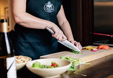 person using a large knife to chop up greens