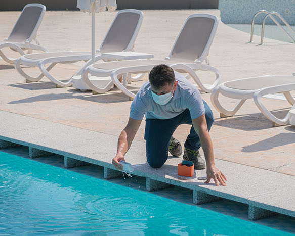 person in a mask reading a device from the pool