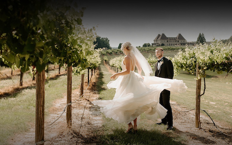 bride twirling in the vineyard with groom standing beside her
