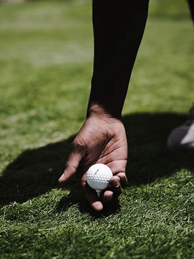 person placing golf tee with ball on it between their fingers