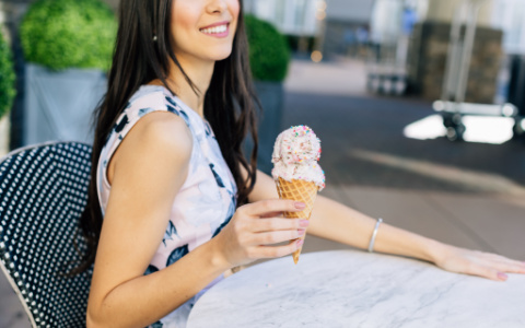 woman sitting at bistro table with ice cream cone