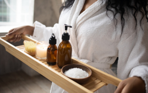 woman in robe holding a tray of spa products