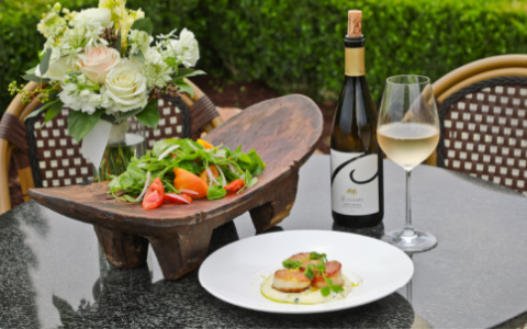 food on bistro table with bottle of white wine and glass