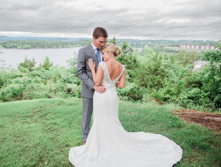 bride and groom on greenery overlooking a lake