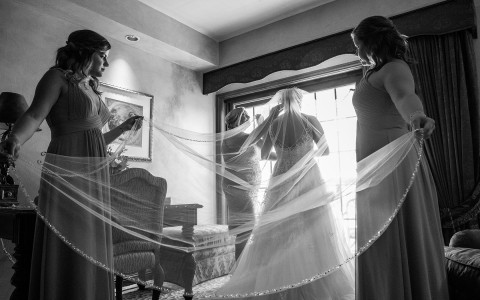 black and white image of bridesmaids holding the brides veil 