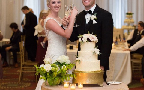 bride and groom standing behind their wedding cake 