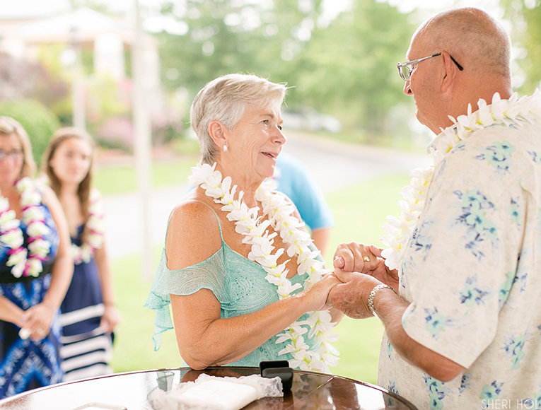 man and woman renew their vowels on a bright day with leis around their necks