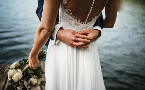 close up shot of bride and groom's hands around her waist