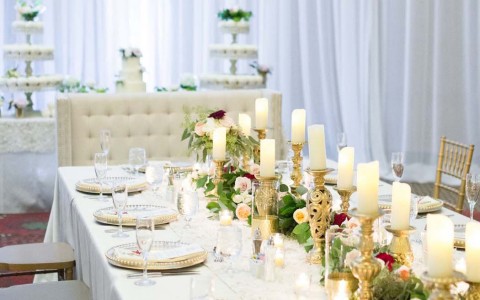 wedding reception table setting with white and gold candles with flowers as the centerpieces
