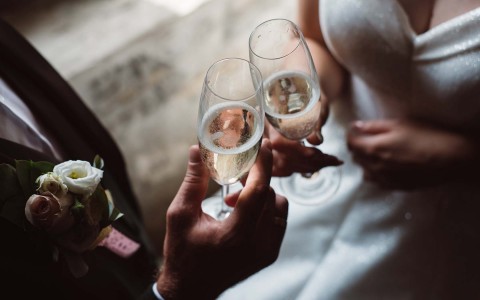 aerial photo of bride and groom toasting with champagne glasses 