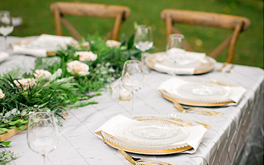 boho wedding reception table setting with green centerpiece and gold plates