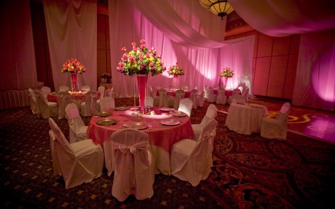 Tables & chairs set for event with pink decor & lighting  