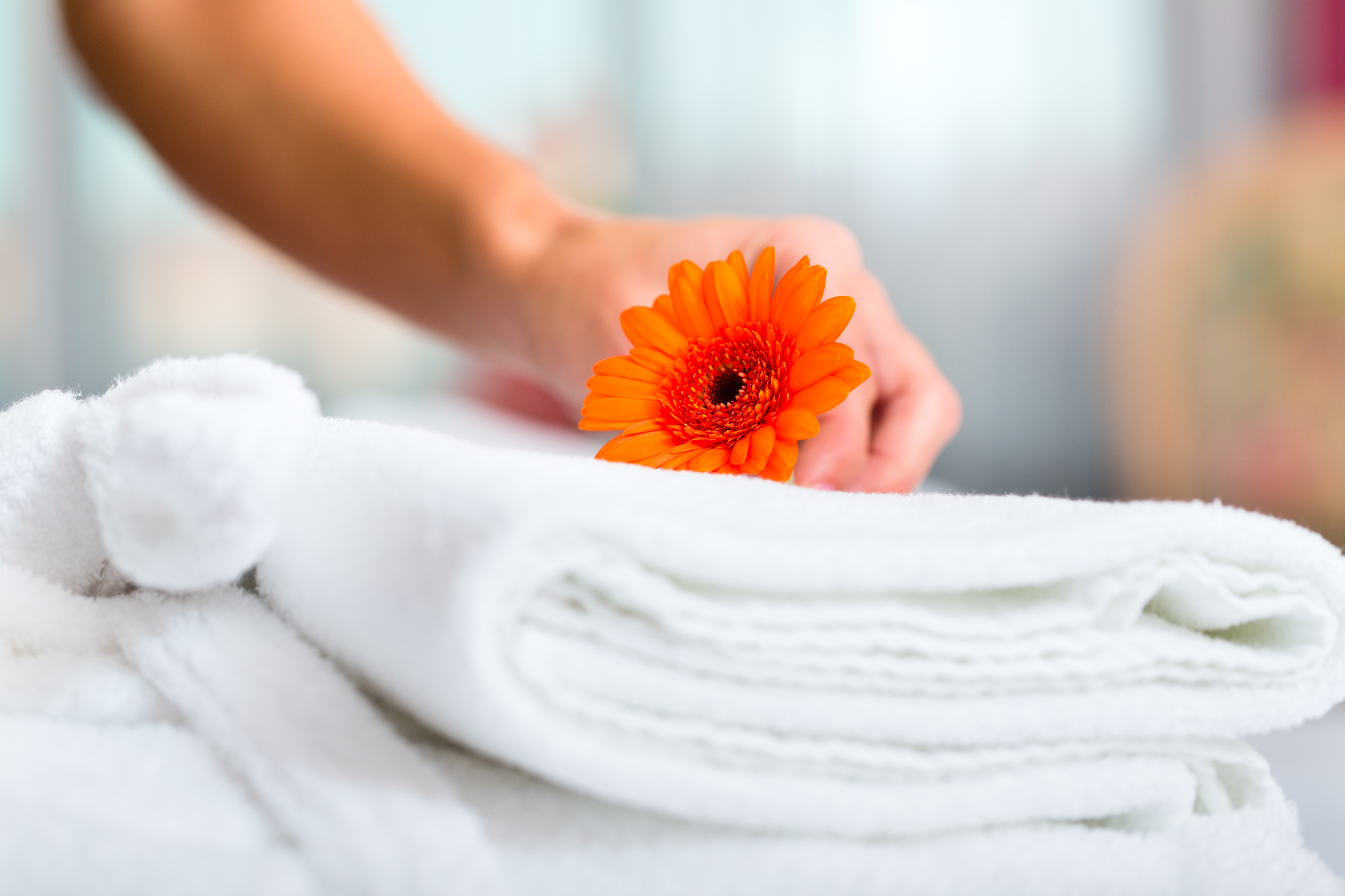 Hand placing orange flower on top of a folded towel