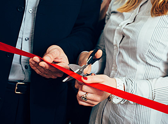 a man and woman cutting a red ribbon