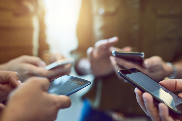 Five people holding cell phones, only their hands are visible