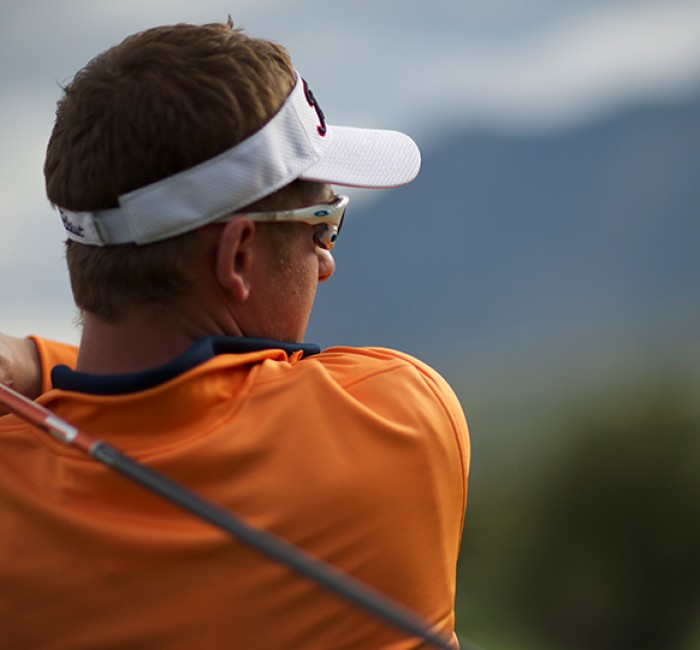 a close up of a golfer watching the ball fly