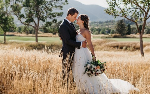 Bride and groom hugging in the middle of grass