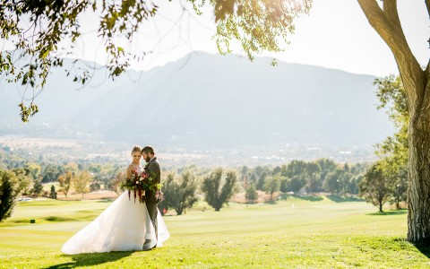 bride and groom embraced with mountains in the background