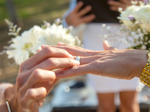 Close up of a bride putting a ring on her bride's hand