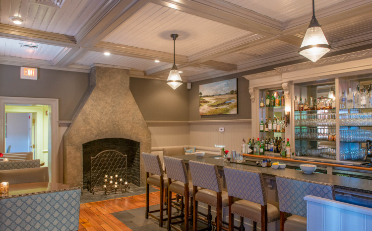 Full bar with padded stools next to fireplace