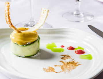 Beautiful plated dish with a cucumber roll and green and red sauces 