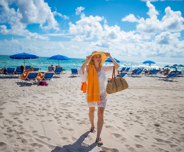 woman walking on the beach in a white dress and hat