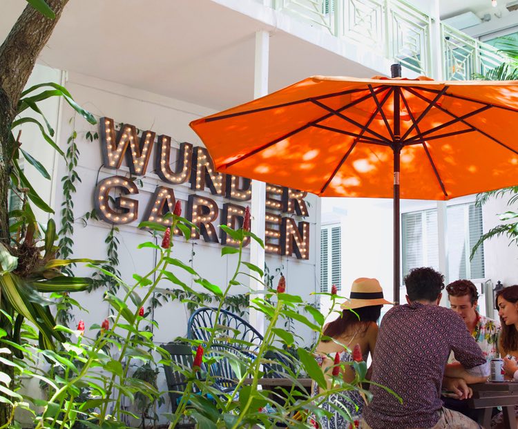 friends sitting a table under an umbrella in the wunder garden