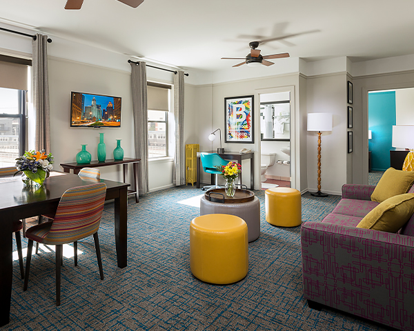 living room in a hotel suite with a purple sofa, yellow chairs and decorated with blue vases