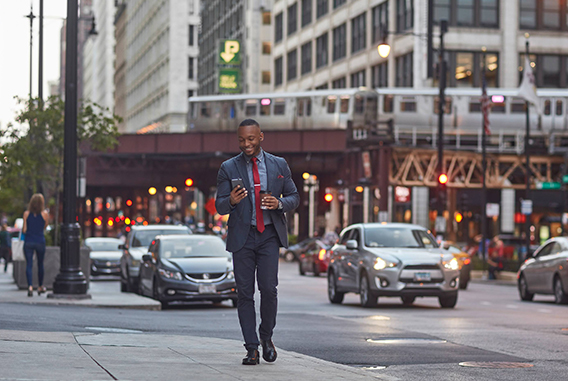 man wearing a suit walking down the street with his phone 