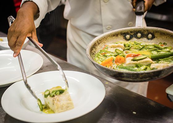 Chef plating food from pan
