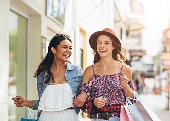 Two young women walking outside with shopping bags