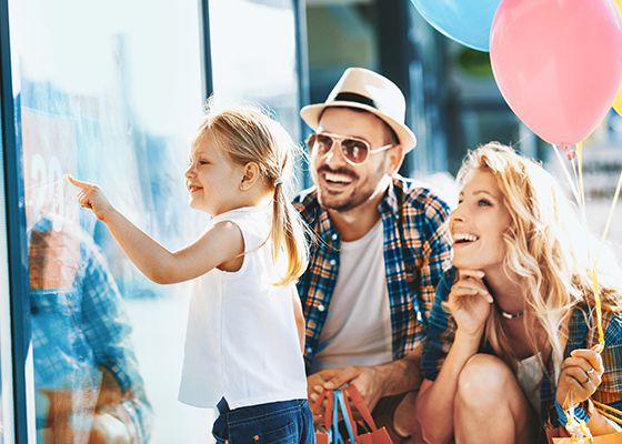 Couple with small daughter pointing at something in store window