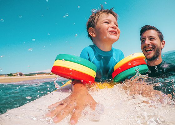 Dad helping young sun stay on surfboard