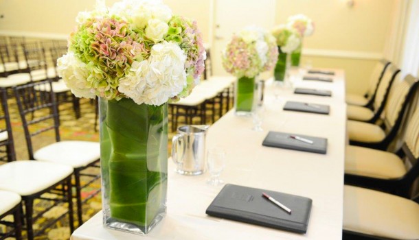 Long rectangular table set with flower arrangements & notepads