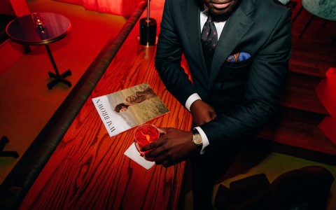 aerial view of person in a suit drinking a cocktail red background