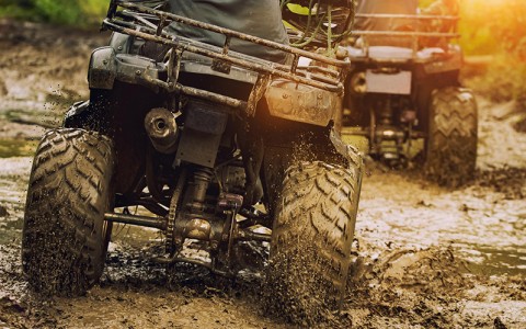 people driving ATVs through muddy terrain