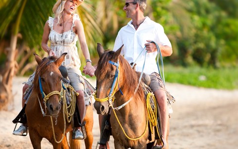 couple horseback riding along beach