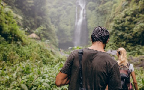 man hiking in remote area towards a waterfall