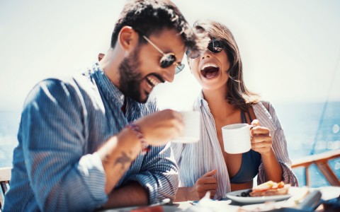 man and woman laughing while enjoying breakfast