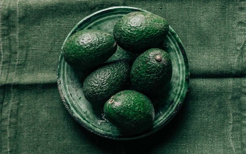 avocados in a green plate with a green background