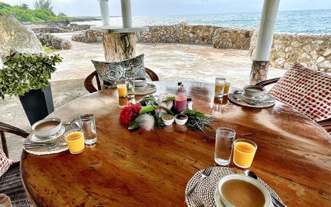 table set up with a soup plate, water and juice glasses besides the beach